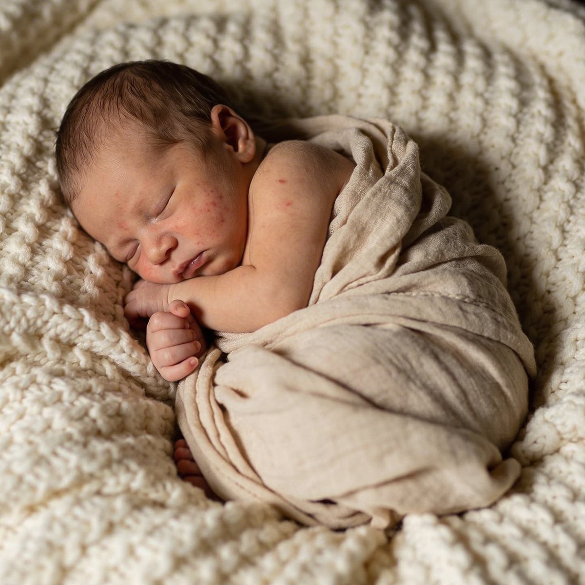 Bebé recién nacido dormido en una pose artística acurrucada, fotografiado entre 5 y 15 días